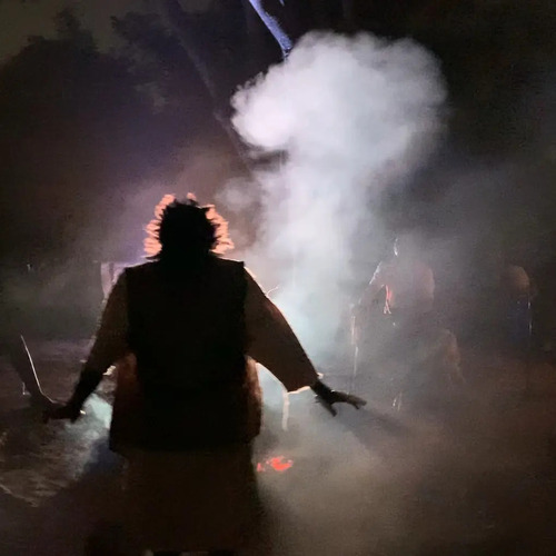 A silhouette stands in front of a plume of smoke and seems to be taken by a spirit.