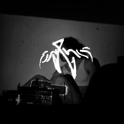 An image of a person sitting silhouetted to the camera with a styled Gregorian 'Jani' over their face